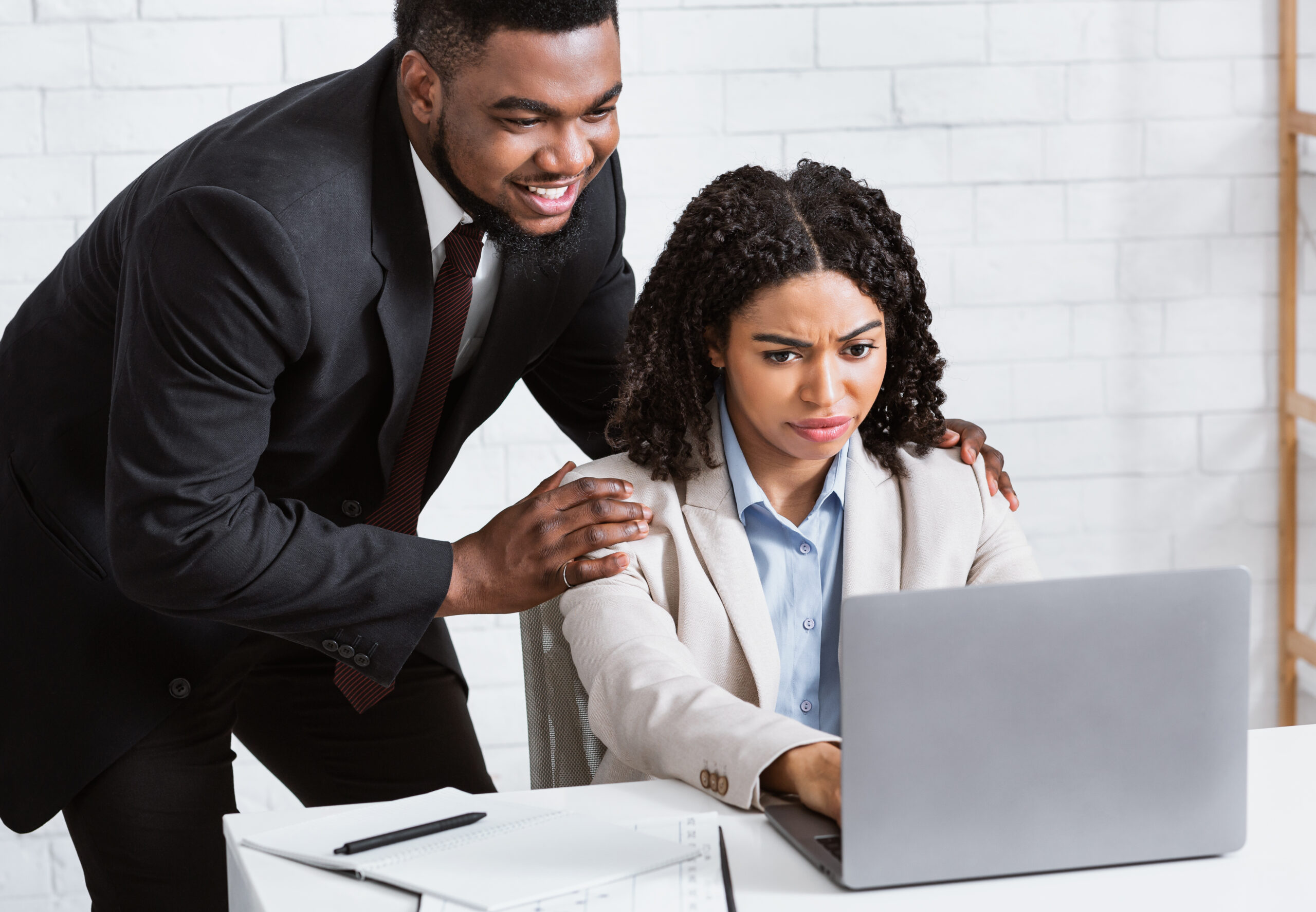 Sexual harassment at workplace. African American male boss touching his female secretary at company office